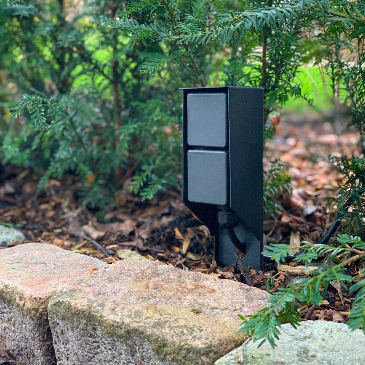Schwarze Gartensteckdose für den Außenbereich mit praktischem Spike und zwei Stromanschlüssen.