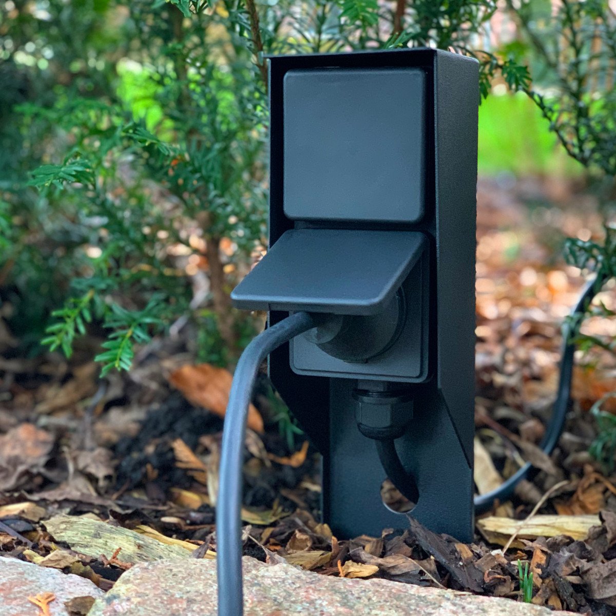 Schwarze Gartensteckdose für den Außenbereich mit praktischem Spike und zwei Stromanschlüssen.